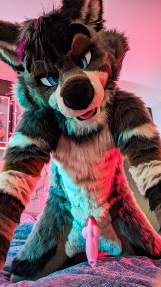 Grey wolf murrsuit lifestyle photo featuring a pink sheath fantasy silicone toy accessory with playful bedroom lighting and colorful cosplay atmosphere